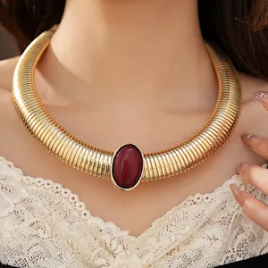 Primo piano di una collana a coste dorata con una pietra centrale ovale rossa