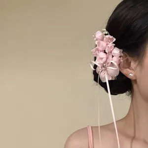 Side view of elegant pink chiffon flower hair clip with satin ribbons and rhinestone detail