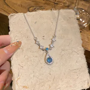 Primo piano di un'elegante collana in argento con ciondolo in cristallo blu a forma di goccia