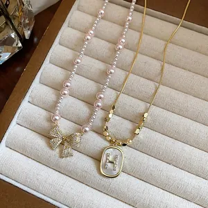 Close-up detail of a pearl bow necklace and gold H letter pendant with zircon