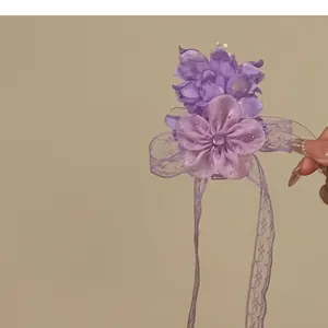Close-up view of purple chiffon flower hair clip with intricate lace and rhinestone details
