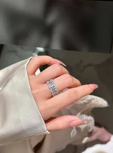 Close-up of a wide silver band ring with sparkling cubic zirconia on a finger.