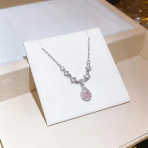 Primo piano di una collana con pendente in cristallo rosa a goccia e pietre lucenti