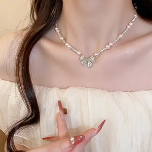 Close-up of elegant pearl necklace with sparkling zircon bow pendant on model's neck