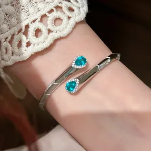 Primo piano di un elegante bracciale rigido argento con due zirconi blu a goccia