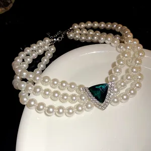 Close-up detail of a vintage three-layer pearl choker necklace with green triangular stone