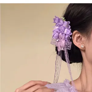 Close-up of elegant purple chiffon flower hair clip with lace ribbons on model's hair.