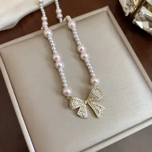 Elegant pearl necklace featuring a sparkling zircon bow pendant on a beige display box