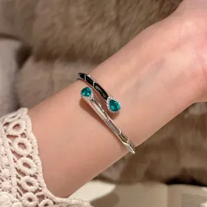 Vista dettagliata di un elegante bracciale in argento con zirconi verdi a goccia