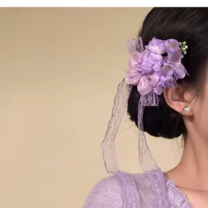 Close-up detail of a purple chiffon flower hair clip with elegant long lace tassels.