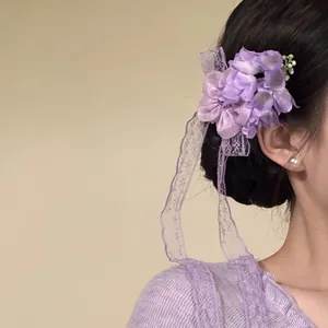Detailed view of an elegant purple fabric flower hair clip with lace ribbon on a model.