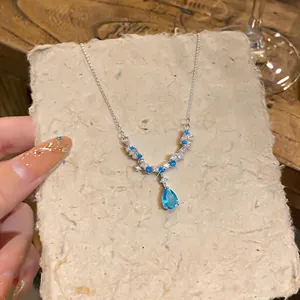 Dettaglio di collana in argento con pendente a goccia in cristallo blu e pietre trasparenti