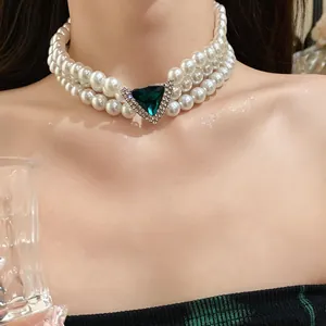 Close-up detail of vintage 3-layer pearl choker with a green triangle gemstone center