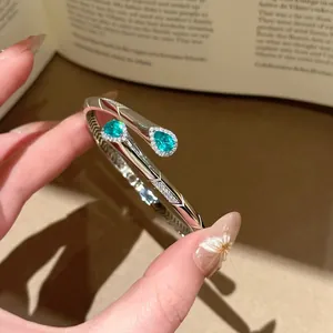 Elegante bracciale aperto color argento con due pietre di zircone verde a goccia