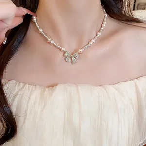 Detail view of an elegant pearl necklace featuring a zircon-studded bow pendant on a model's neck