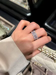 Macro view of an elegant silver zircon geometric ring worn on a finger with a luxury bag