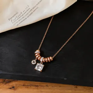 Gros plan d'un collier élégant en or rose avec un pendentif en pierre carrée transparente