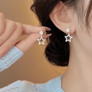 Gros plan de boucles d'oreilles pendantes en étoile avec zircons portées par un modèle