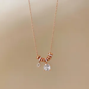 Détail d'un collier pendentif en or rose avec un charme en cristal carré scintillant élégant