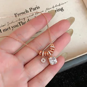 Gros plan d'un collier en or rose avec un cristal carré et des breloques serties