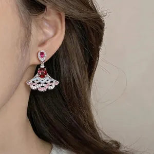 Elegant silver fan-shaped drop earrings with red crystals on model for a luxury look
