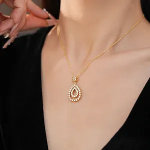 Dettaglio di una collana con ciondolo a goccia dorato e zirconi indossata da una modella.