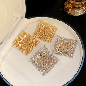 Detailed macro view of gold and silver geometric sequin tassel earrings in a jewelry box