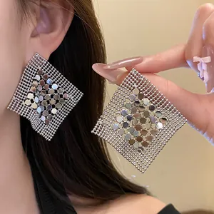 Close-up detail of silver geometric mesh earrings featuring a metallic sequin center design