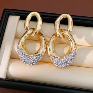 Elegante goldene hohle Tropfenohrringe mit Strass und Silbernadeln in Schmuckschatulle
