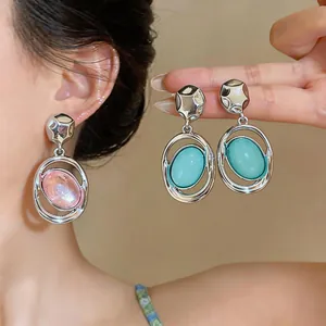 Detailed macro view of elegant silver-toned earrings featuring pink and light blue oval stones.