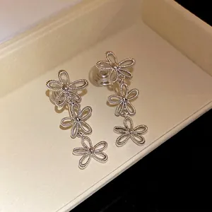 Elegant silver hollow flower fringe clip-on earrings displayed in a light beige jewelry tray