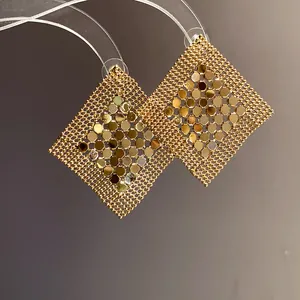 Close-up view of golden geometric sequin mesh earrings with a shiny metallic finish.