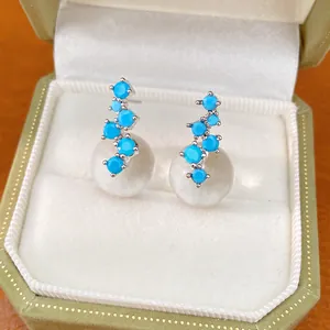 Detail shot of blue zircon and clear resin sphere stud earrings in a green velvet box