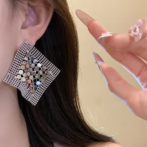 Detailed view of geometric silver sequin mesh earrings being worn on model for scale