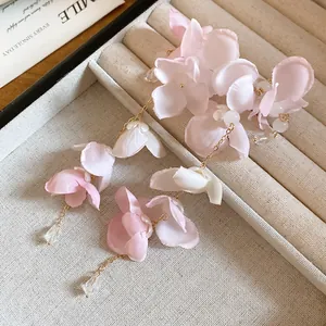 Gros plan de boucles d'oreilles fleurs en tissu rose avec gouttes en cristal dans un plateau