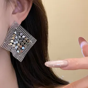 Close-up detail of geometric silver mesh earrings with shimmering metallic sequins decoration