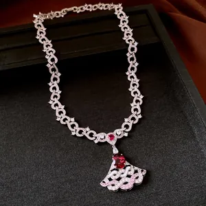 Elegant fan-shaped pendant necklace with red zircon and sparkling stones on a black tray
