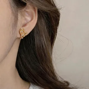 Elegant 18k gold plated heart stud earrings with sparkling zircons worn for a close-up view