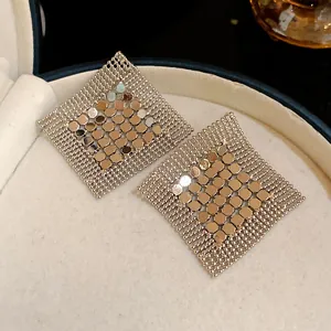 Close-up of geometric silver sequin mesh tassel earrings with metallic luster