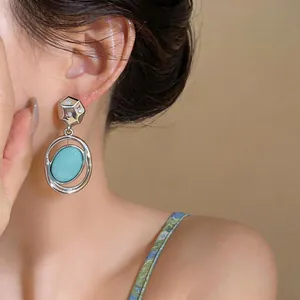 Close-up of elegant silver drop earrings with a large oval turquoise stone