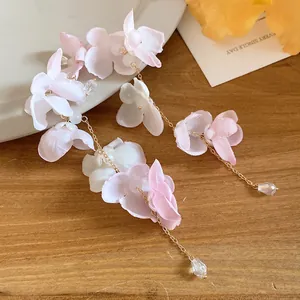 Gros plan sur les boucles d'oreilles fleurs en tissu rose et blanc avec cristal