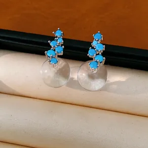Macro detail of silver needle earrings with blue stones and clear resin beads