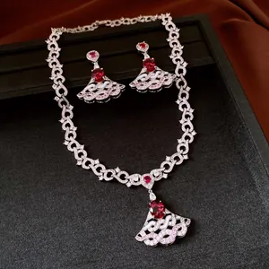 Elegant fan-shaped jewelry set with red gemstones and pavé crystals on black background