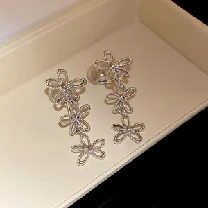 Macro view of silver hollow flower fringe drop earrings with three flower charms