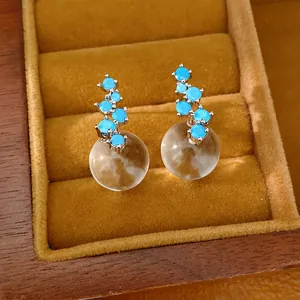 Detailed macro view of blue zircon and translucent resin ball stud earrings in a box