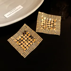 Close-up of golden geometric sequin mesh earrings with reflective metallic finish
