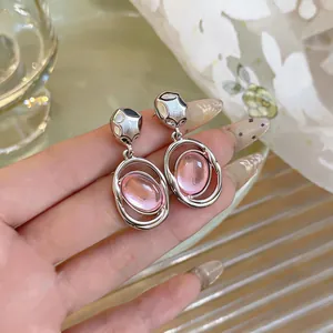 Close-up of silver orbital earrings featuring translucent pink oval stones