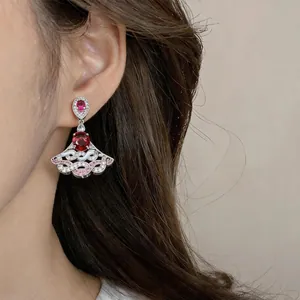Detailed view of luxury fan-shaped earrings with red gemstones and sparkling zircons