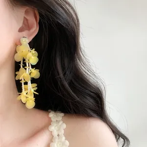 Close-up detail of elegant yellow glass bead tassel earrings worn on a model's ear