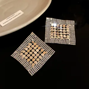 Macro detail of geometric silver sequin mesh square earrings on black surface